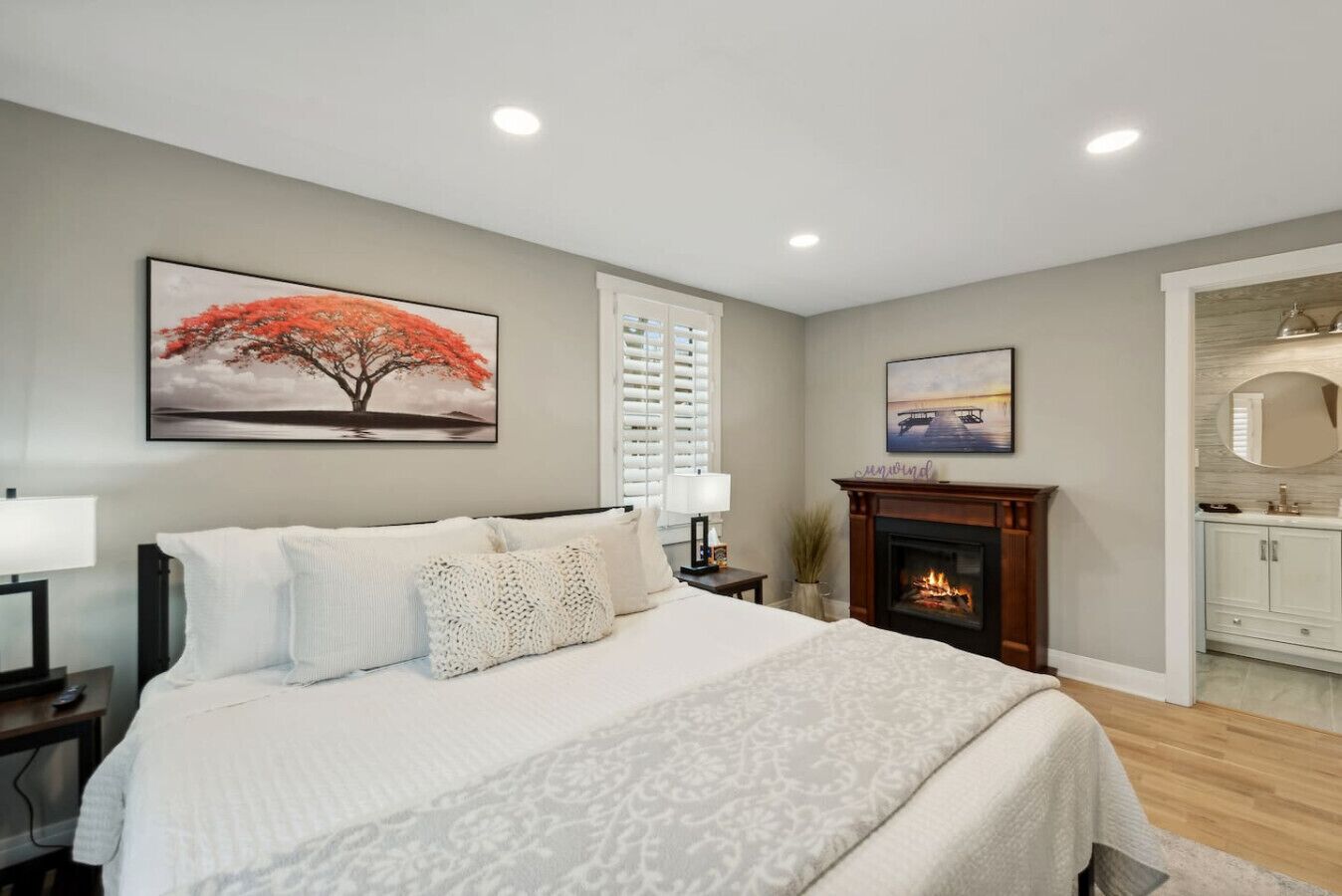A bedroom with a bed, a fireplace, and a painting on the wall.
