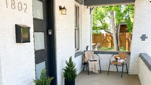 A covered porch with a door marked '1802,' two potted plants, a small table with chairs, and a 'WELCOME' mat. - Huge 6BR Highlands Home - Modern Style & Comfort (Denver)
