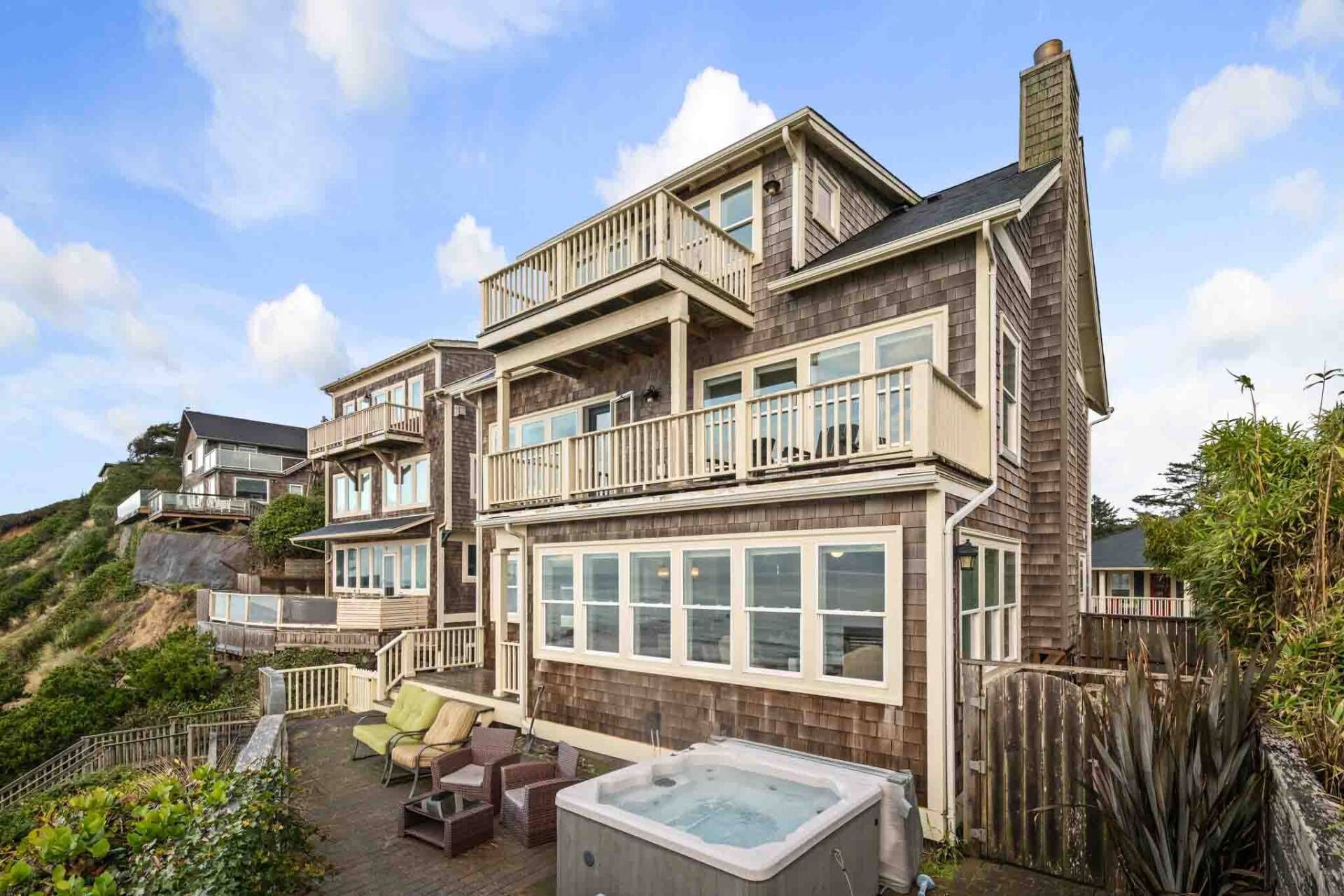 Een meerlaags huis met een balkon, een jacuzzi en een terras met tuinmeubilair.