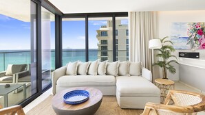 Ein modernes Wohnzimmer mit großem Fenster, einer Couch, einem Couchtisch und Blick auf den Ozean.