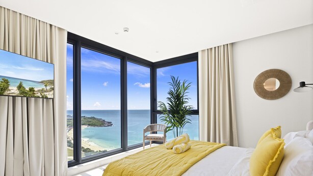 Ein Schlafzimmer mit einem großen Fenster, das Blick auf Strand und Meer bietet.
