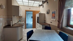 Una cocina con mesa de comedor, armarios y ventana con cortinas.
