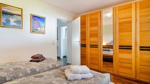 Un dormitorio con dos camas, un armario de madera y dos cuadros enmarcados en la pared.