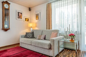A living room with a sofa, a glass coffee table, a clock, and framed artwork on the wall. - Apartment 'Fewo Wegen' with Mountain View, Private Terrace & Wi-Fi (Salem)
