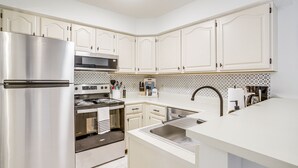 A modern kitchen with white cabinetry, stainless steel appliances, and a patterned backsplash. - Porch & Water Views: Getaway in Mallard Lakes (Selbyville)