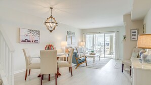 A spacious living room with a dining area, a chandelier, and a view to the outside. - Porch & Water Views: Getaway in Mallard Lakes (Selbyville)