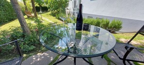 A glass table with two wine glasses and a bottle in a garden setting. - Studio Apartment 'Ferienwohnung Vino9' with Private Garden and Wi-Fi (Vogtsburg im Kaiserstuhl)