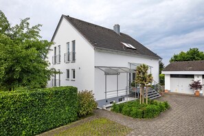 A two-story house with a covered porch, a garage, and a well-maintained garden. - Studio Apartment 'Ferienwohnung Vino9' with Private Garden and Wi-Fi (Vogtsburg im Kaiserstuhl)