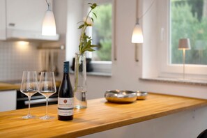 A kitchen counter with wine glasses, a bottle, and a vase with a plant. - Studio Apartment 'Ferienwohnung Vino9' with Private Garden and Wi-Fi (Vogtsburg im Kaiserstuhl)