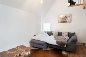 A modern living room with a grey sofa, a cowhide rug, and a bull-themed artwork on the wall. - Apartment 'Appartment Waldloft' with Mountain View, Private Terrace and Wi-Fi (Bühlertal)