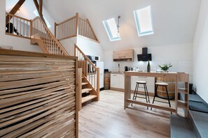 A modern kitchen with wooden features, a central island, and a staircase. - Apartment 'Appartment Waldloft' with Mountain View, Private Terrace and Wi-Fi (Bühlertal)