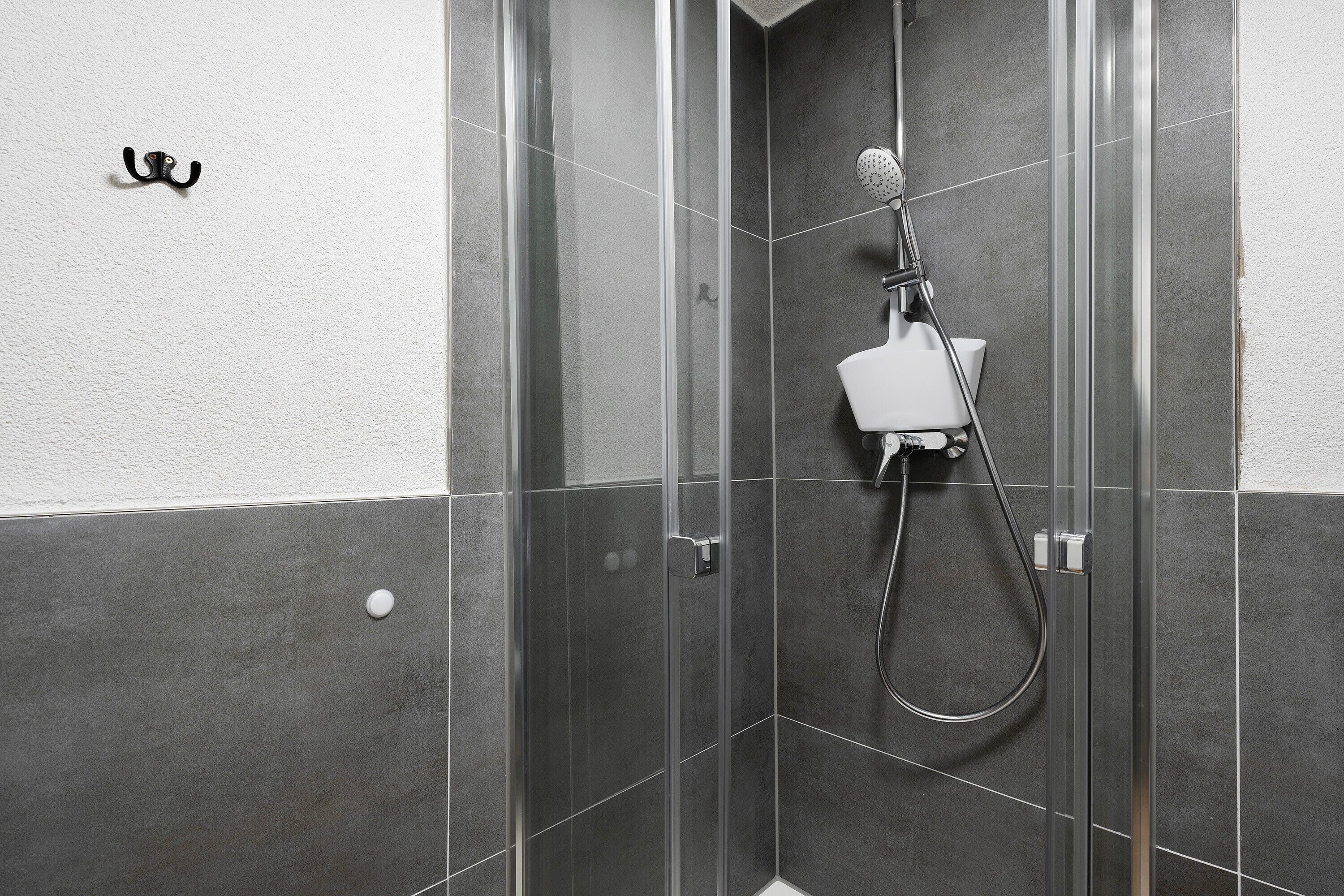 Une douche avec un pommeau de douche amovible, un porte-serviettes mural et des toilettes blanches.