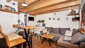 Un salón acogedor con techo de madera, un sofá, una mesa de centro y un comedor con mesa y sillas.