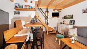 Una habitación acogedora con un banco de madera, una mesa, un sofá, un televisor y una escalera.