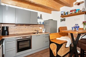 A modern kitchen with grey cabinets, a wooden countertop, a built-in oven, and a coffee maker.