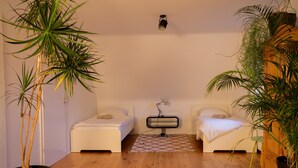 Een kamer met twee bedden, een elektrische kachel en potplanten.