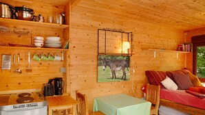 A wooden cabin interior with a kitchen, dining area, and a bed.