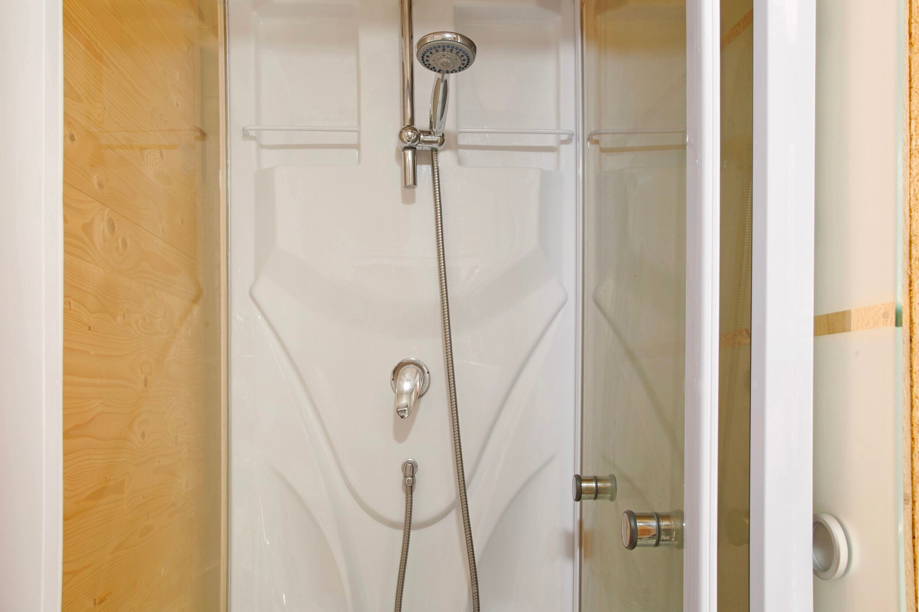 A shower with a handheld showerhead and a wall-mounted faucet.