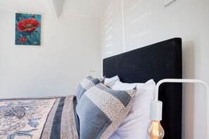 Une chambre à coucher avec un lit, une table de chevet, une lampe et un tableau au mur.