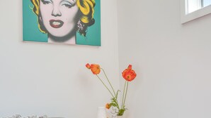 A living room with a grey sofa, a red armchair, a table with a vase of flowers, and a painting on the wall. - Classy Modern Unit.  Walk to shops, bars & cafes.  Pet-Friendly! Bus at gate. (Christchurch)