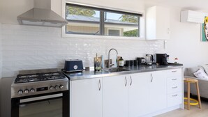 A modern kitchen with white cabinets, a stainless steel stove, and a window above the sink. - Classy Modern Unit.  Walk to shops, bars & cafes.  Pet-Friendly! Bus at gate. (Christchurch)