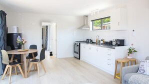 A modern kitchen with white cabinets, a built-in oven, and a window above the sink. - Classy Modern Unit.  Walk to shops, bars & cafes.  Pet-Friendly! Bus at gate. (Christchurch)