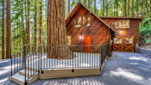 Una cabaña con fachada de madera, una terraza y una escalera que conduce a la entrada.
