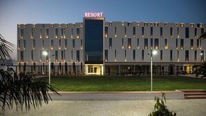 Un hotel moderno con techo plano, entrada central y césped bien cuidado.
