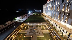 Un patio con una fuente geométrica, una zona de estar y un edificio de fachada moderna.