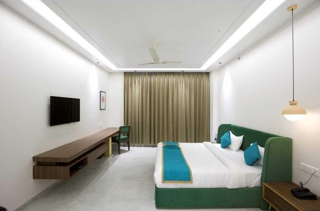 Una habitación de hotel moderna con una cama, un escritorio, una silla y un televisor montado en la pared.