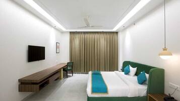 Una habitación de hotel moderna con una cama, un escritorio, una silla y un televisor montado en la pared.