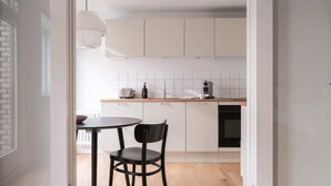 A modern kitchen with white cabinets, a round table, and a black chair.