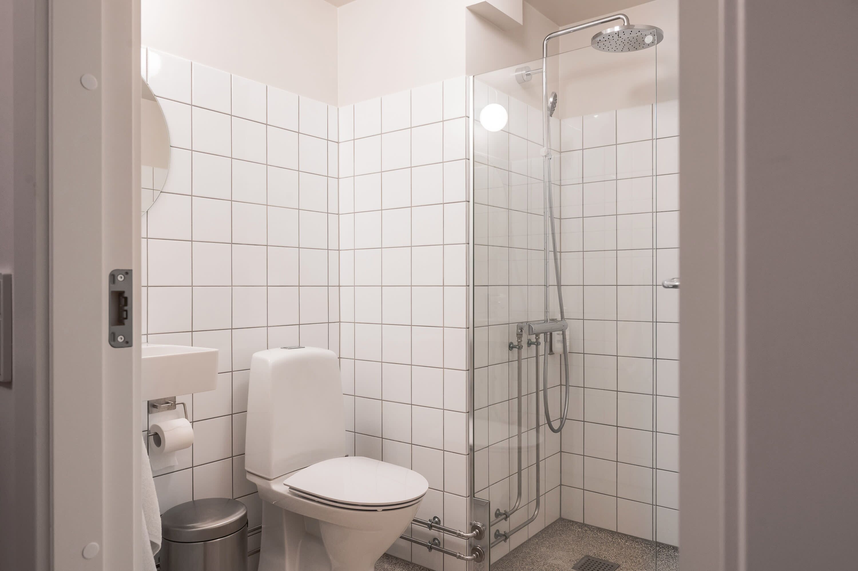 Een moderne badkamer met toilet, douche en wastafel.