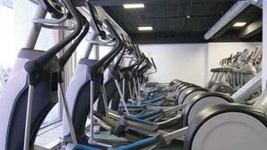A row of stationary bikes in a gym with a white ceiling and walls.