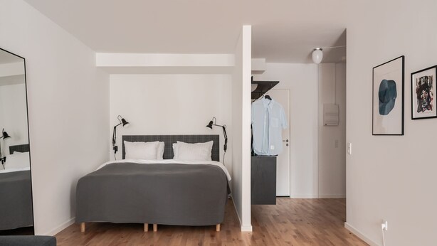 Een moderne slaapkamer met een groot bed, een nachtkastje, een stoel en een kledingkast.