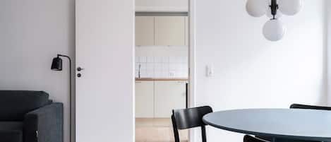 Una cocina moderna con armarios blancos, una mesa redonda con sillas y una lámpara de pie negra.