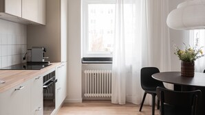 Moderni keittiö, jossa on valkoiset kaapit, puinen työtaso ja ikkuna, jossa on läpikuultavat verhot.