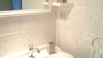 Un baño con lavamanos blanco, un espejo y una cortina azul.