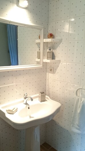 A bathroom with a white sink, a mirror, and a blue curtain. - La Boissière et le Vialat (Montagnac)