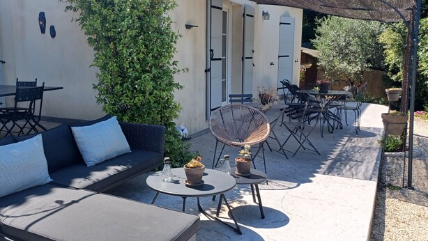 Een terras buiten met een bank, een eettafel, stoelen en een loungestoel.