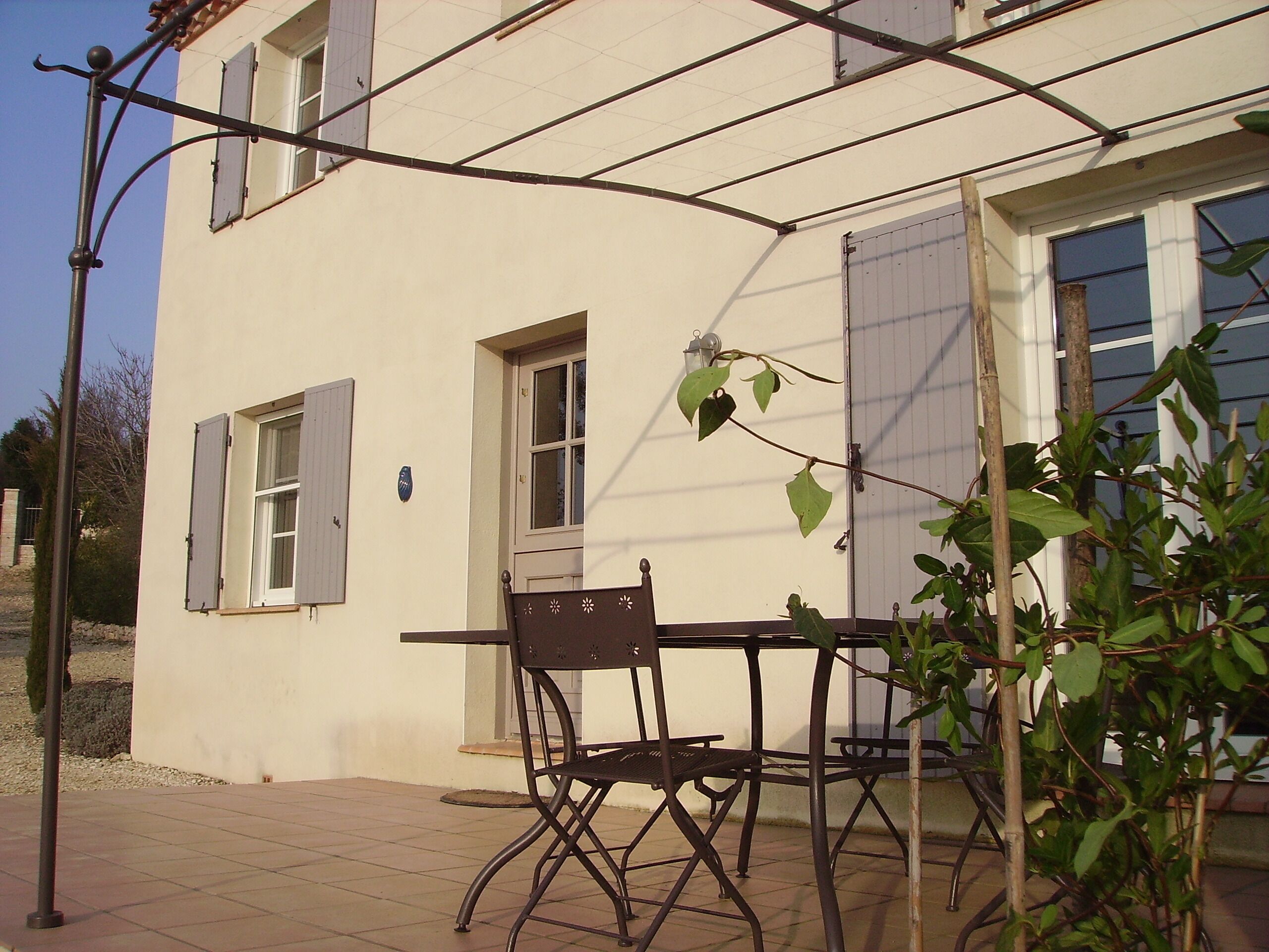 A patio with a table and chairs, a lamp post, and a building with windows and shutters.