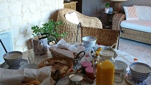 Ontbijt met diverse gerechten, een rieten stoel en een bank in een kamer met een stenen muur en een lamp.