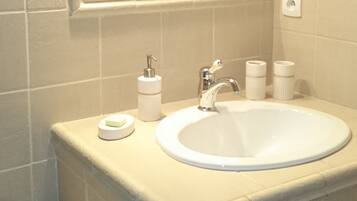 Un baño con un lavamanos blanco, un espejo y un toallero.