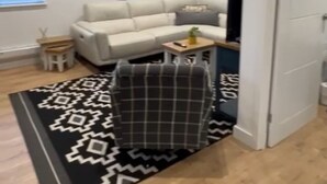 A modern living room with a sofa, a small table, and a patterned rug.