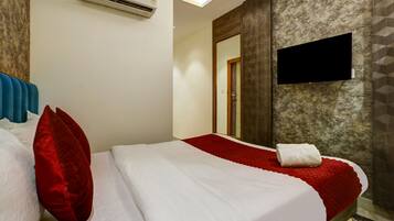 Quarto de hotel com cama, televisão de tela plana e ar condicionado.