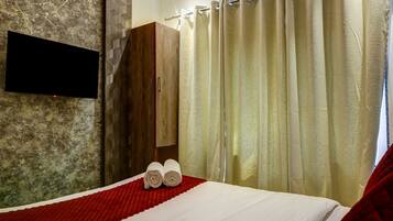 Una habitación de hotel con cama, televisor montado en la pared y armario.