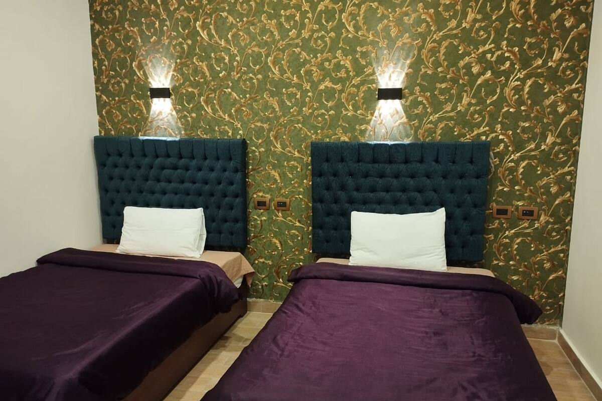 A room with two beds, each with a dark headboard and a white pillow.