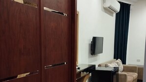 A room with a wooden wardrobe, a flat-screen TV mounted on the wall, a beige sofa, and a small black table. - Richmond Down Town  (Cairo)