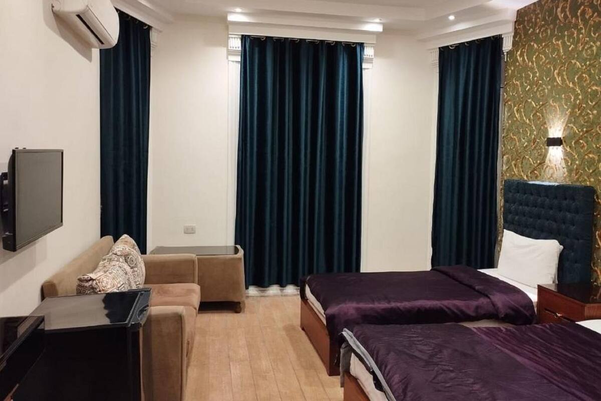 A hotel room with a bed, a sofa, a desk, and a TV.