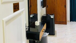A hotel room with a white door marked with the number 412, a black desk with a mirror, a black telephone, and a trash bin. - Richmond Down Town  (Cairo)